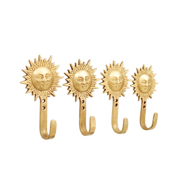 A set of four bohemian sun brass wall hooks. Each is topped with a sunburst with lines framing the rays and detailing a...
