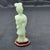 Chinese jade carving resting on a wood base in the form of a standing lady holding a lotus flower, likely depicting the...