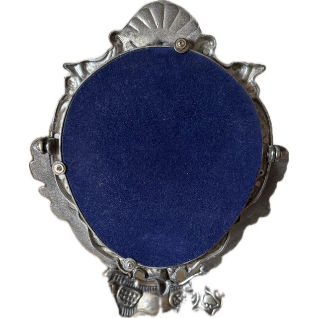 Antique silverplate tabletop vanity mirror with an ornate Rococo Revival frame featuring three cherub figures, scrolling...