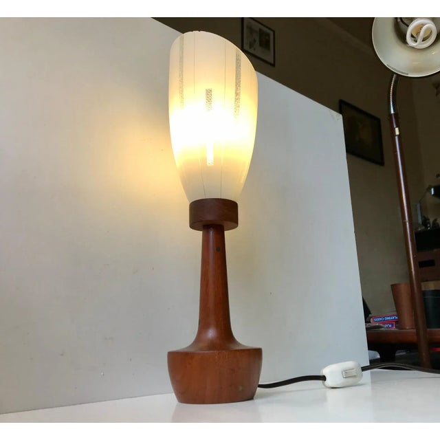 Table Lamp composed of a solid teak base with brass inserts and a striped angled single layered glass shade. It was...