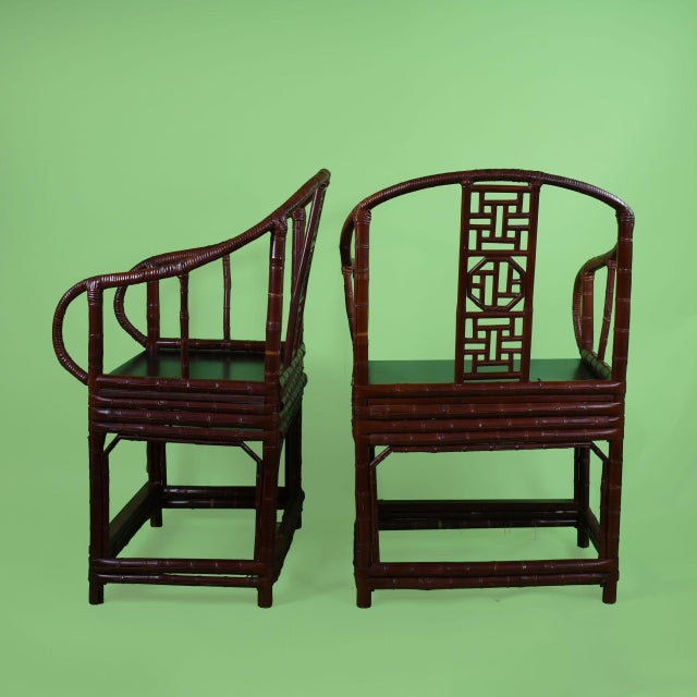A pair of chinoiserie barrel chairs in deep burgundy, their curved barrel backs wrapping around plush, comfortable seats....
