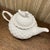 Grace Tea Wear cream-colored ceramic teapot with lattice design and bird lid