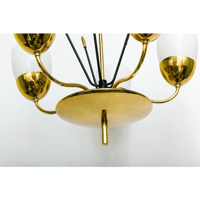 An elegant solid brass and milky glass five-arm chandelier in the manner of Paavo Tynell.