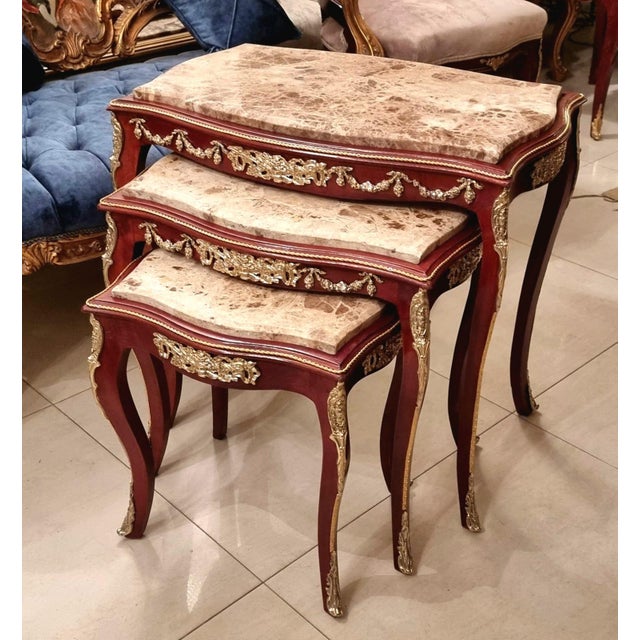 Elegant Rococo style nesting tables featuring a luxurious set of three accent tables topped with sophisticated beige and...