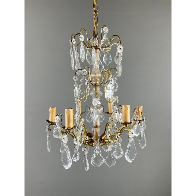 An elegant bronze and brass chandelier adorned with numerous cut crystal pendants, crafted in the Louis XV style during...