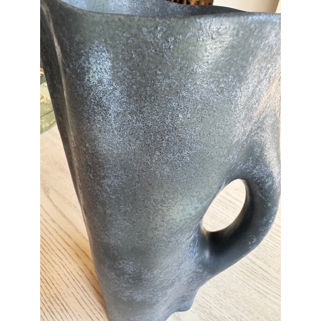 Made by L'Objet. Porcelain Timna pitcher, available in the stone and iron finishes, extend the organic forms and mineral...