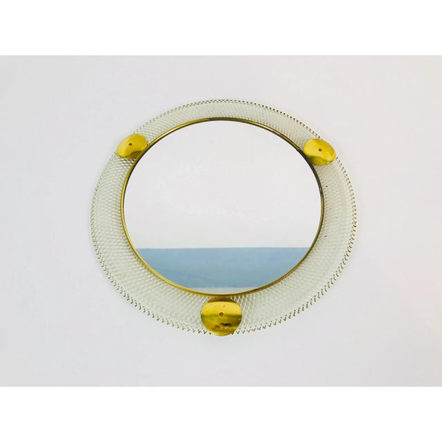 A round wall mirror from the 1960s made in Italy. The mirror has a circular metal design. The mirror is in a good vintage...