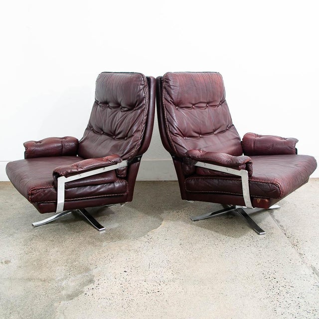 Arne Norell lounge chairs in chrome and burgundy leather. Each chair swivels 360 degrees. Comfortable set in fantastic...