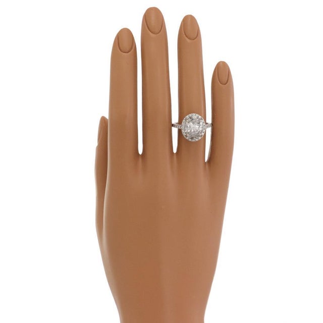 This is a stunning engagement halo ring, crafted from platinum with a polished finish featuring an oval shape top and...