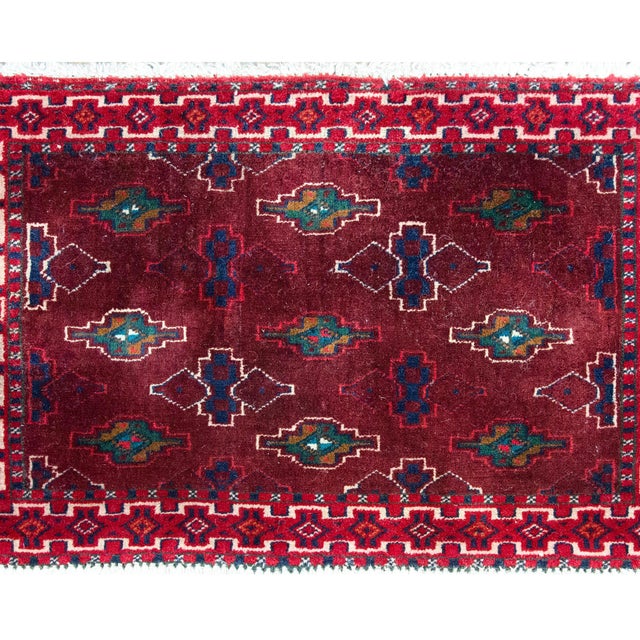 A charming petite Persian Turkmen rug with a field covered in a repeated tribal design and surrounded by a border with...