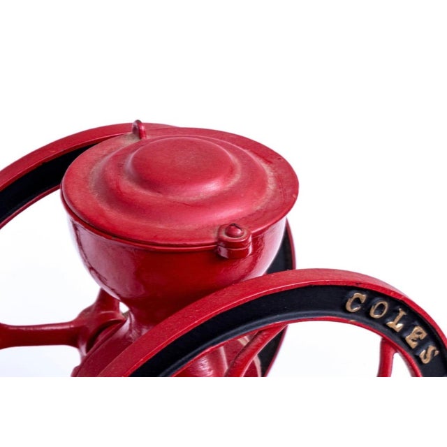 A wonderful antique Iron Coles Mfg. Co. coffee grinder featuring a red painted cast iron body with a pivoting lid and...