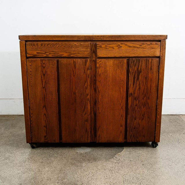 Expanding rolling server with black laminate central surface. The bottom section offers a large drawer s well as storage....