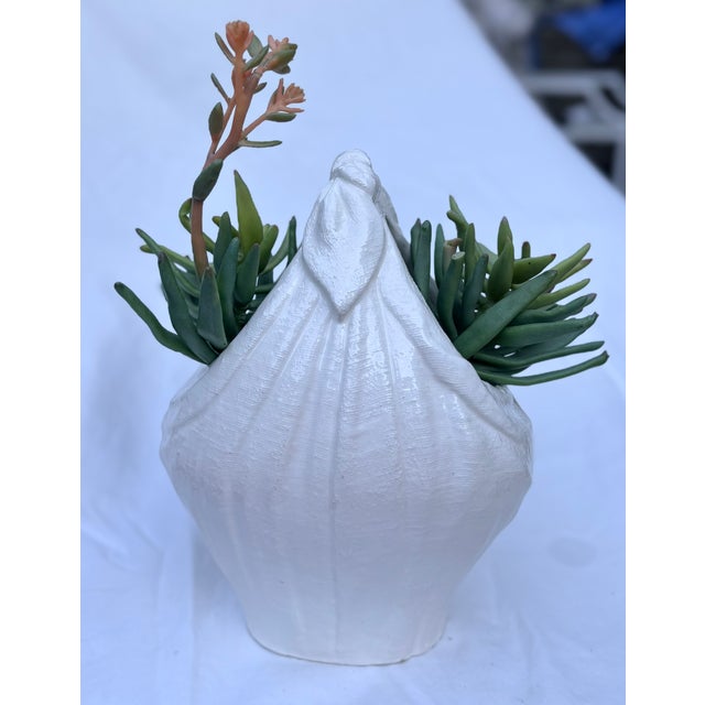 This chic trompe-L'oeil white ceramic vase appears to be a knotted linen satchel. The detail of the piece from the texture...