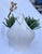 This chic trompe-L'oeil white ceramic vase appears to be a knotted linen satchel. The detail of the piece from the texture...