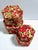 A striking set of four vintage nesting boxes covered in vivid red-and-green floral cotton textile. The graduated hexagonal...