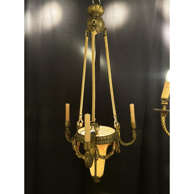 A three-arm gilt bronze pendant light in the form of a conical bowl. The blown glass shade, decorated with floral motifs...