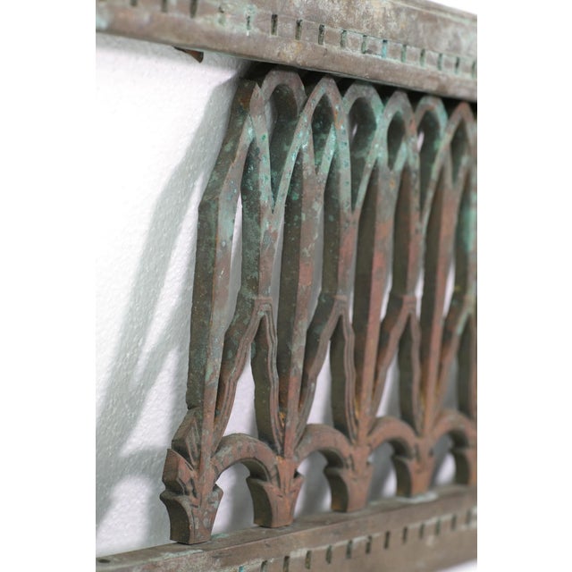 Bronze wall grate with ornate details in a rectangular frame. Some of the ornate pieces are missing. The original mounting...