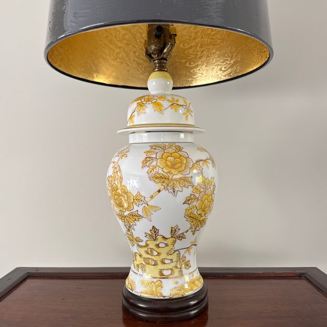 Vintage Chinese yellow, white and gold floral ginger jar lamp with new black shade. The porcelain ginger jar stands 16.5”...