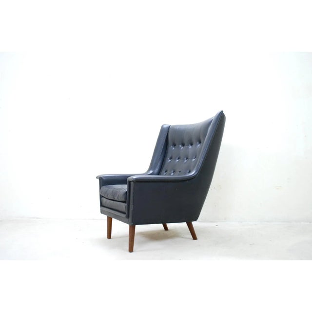 This Wingback Armchair has references to the Papa Bear Chair. It is made of black leather and Afromosia wood.