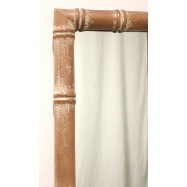 An Asian Influenced wall mirror, unbranded. Mirrored glass in a rectangular shaped whitewashed brown color faux bamboo...
