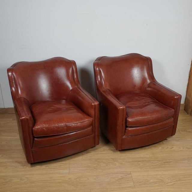 A pair of art deco moustache backed club chairs with chestnut leather upholstery. Dimensions: h 78cm w 71cm d 80cm seat h...