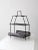 A mid-20th-century metal stand in a sleek black finish, featuring two shelves with an expressive patterned cutout design....