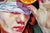 The artwork features a figure with vibrant red hair, blindfolded and holding a halved orange against their forehead. The...
