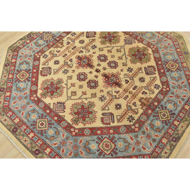 A tribal Caucasian Kazak rug hand-knotted with fine wool on a cotton foundation. This rug features geometric botanical...