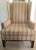 Outscrolled arms, fretwork legs, a t-shaped cushion, stretcher base, and quiet muted striped upholstery create a subtle...