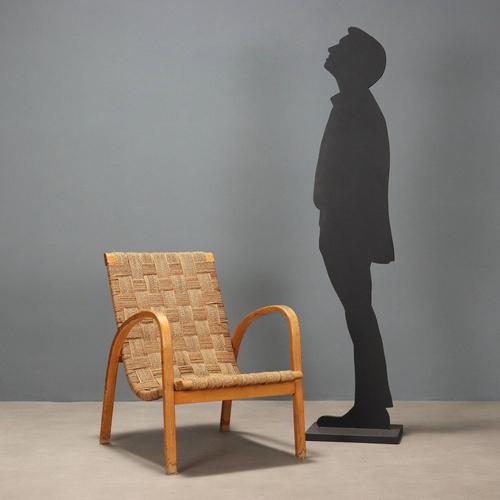 Vintage armchair with exposed wooden armrests and woven rope seat. This piece is attributed to the mentioned...