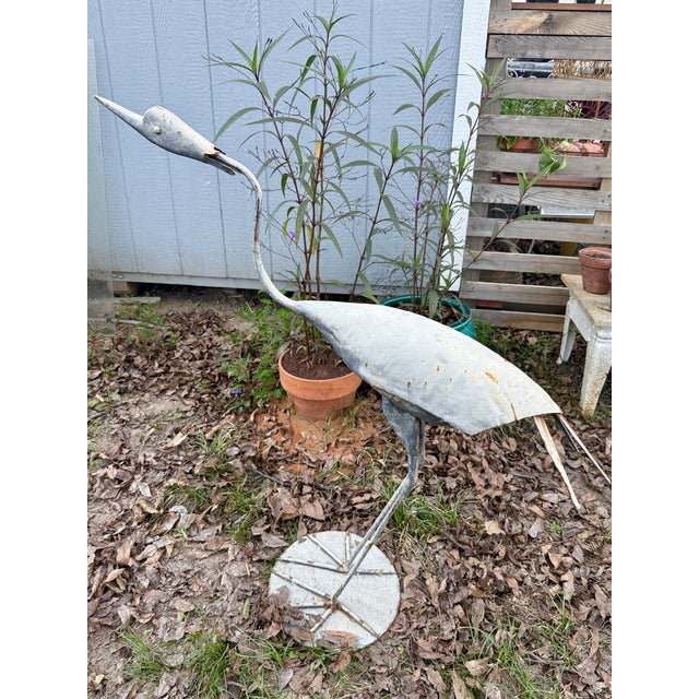 Large handcrafted metal bird sculpture depicting a crane or heron, made from welded and shaped steel with a long curved...