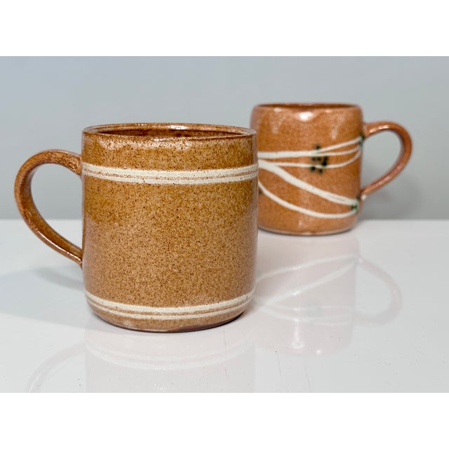 These two handcrafted ceramic mugs bear the distinctive signature of ceramic artist Helma Klett (1908-1996). with their...