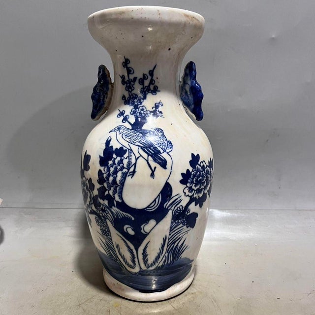A matched pair of porcelain vases on a crisp white ground, hand-painted in underglaze blue with classic bird-and-flower...