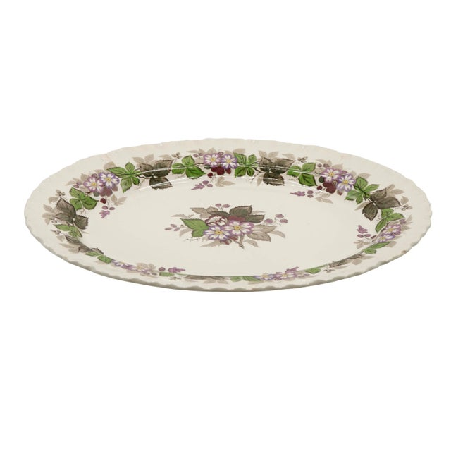 A colorful “Gratewood” pattern English transferware serving platter made by Wedgwood. A central image depicts a small...