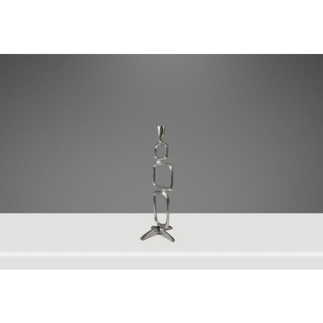 Introducing a captivating sculptural candlestick holder forged from solid aluminum and attributed to accomplished designer...