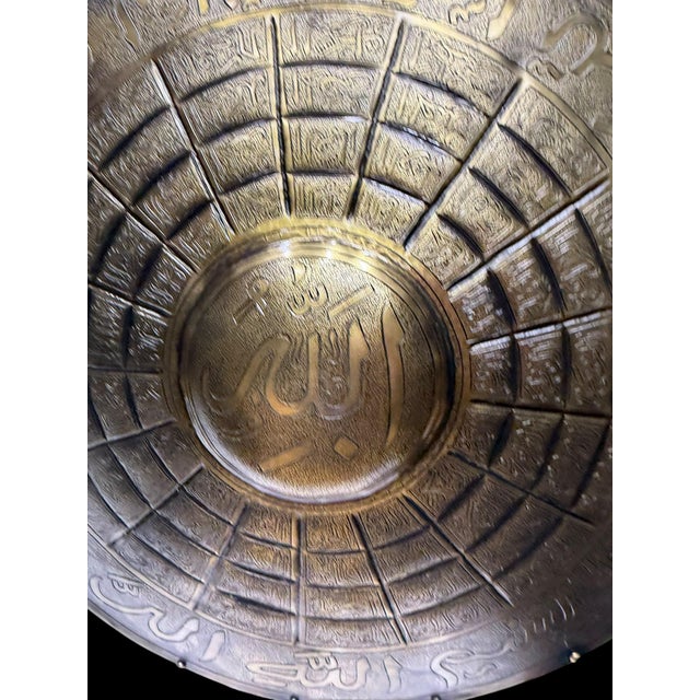 A handmade Turkish brass armor display featuring a domed helmet and round shield mounted on a matching pedestal stand. The...