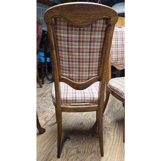 This Pair of Late 19th Century Neoclassical Directoire-Style Walnut Side Chairs With Rosette Mounts is a warm set with...