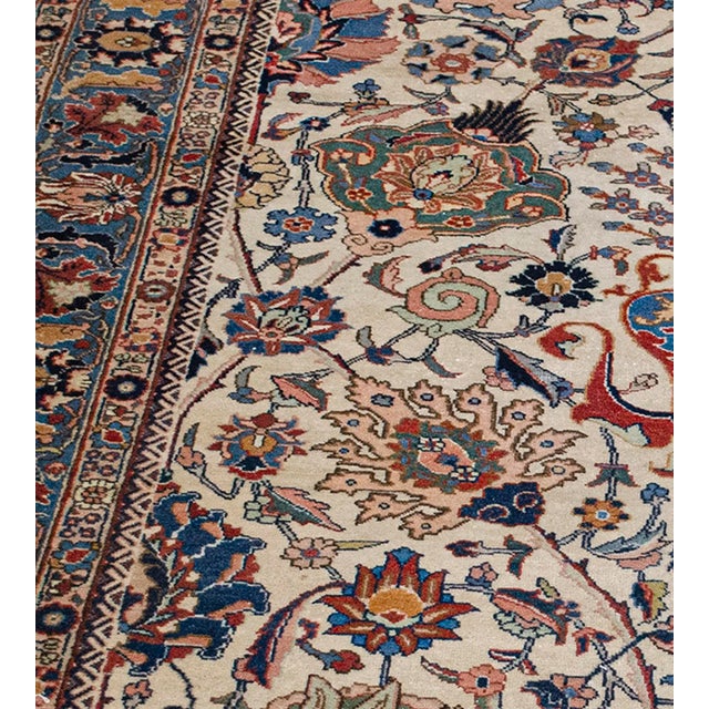 This handwoven antique, circa 1890, Persian Tabriz rug features an ivory field with an overall design with a light blue...