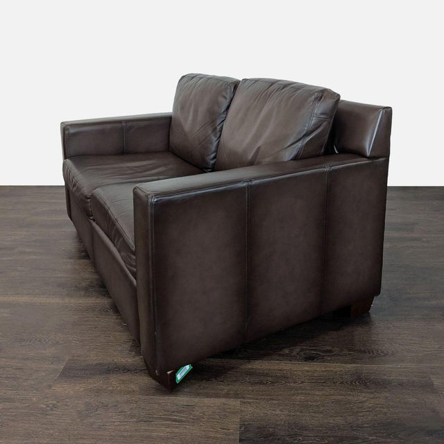 This Pottery Barn loveseat features rich brown leather and a clean, modern design. With plush seat and back cushions, it...