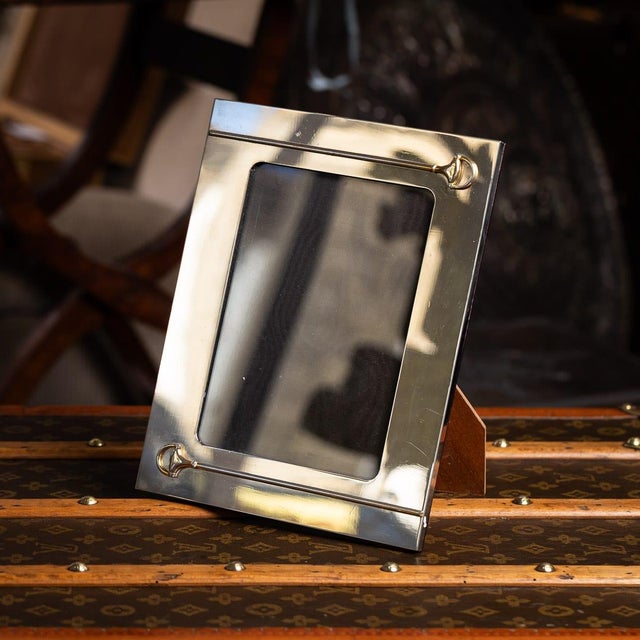 A 20th century silver plated photograph frame by gucci. It has a simple rectangular shape with smooth outer border. Around...