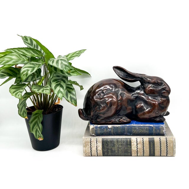 Captivating vintage rabbit sculpture cast in heavy iron with a warm bronze-tone finish. The reclining hare has long ears...