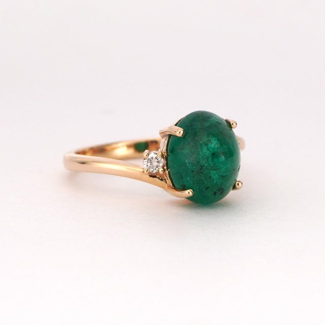 This exquisite 14k yellow gold ring features a captivating cabochon-cut emerald. The emerald weighs 3.33 carats and...