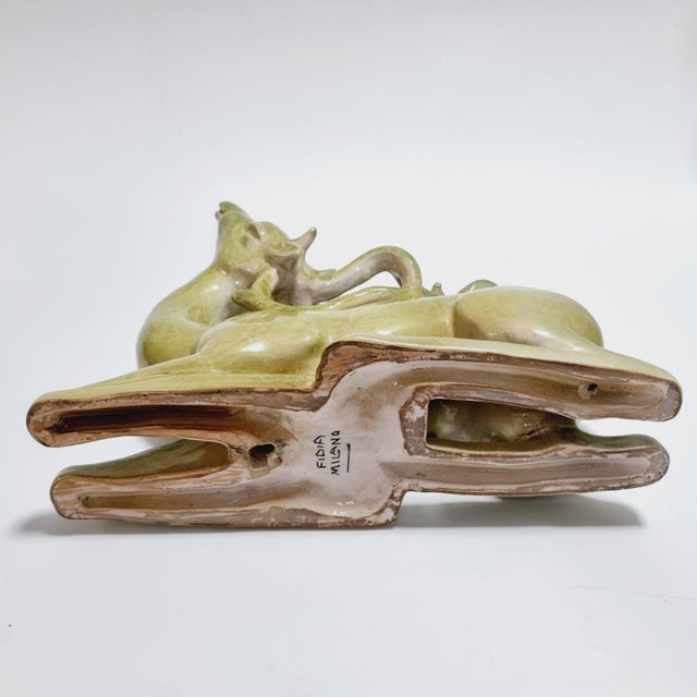 An elegant Italian Art Deco glazed ceramic sculpture depicting a stylized recumbent deer, created by the renowned Fidia...