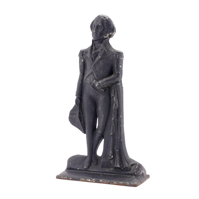 Painted cast iron door stop featuring George Washington posed in military attire. Washington is depicted standing with his...