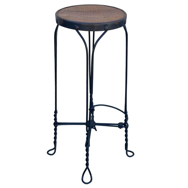 Late Victorian twisted iron metal and oak wood-top ice cream parlor stool features a dark-finished wrought iron base with...