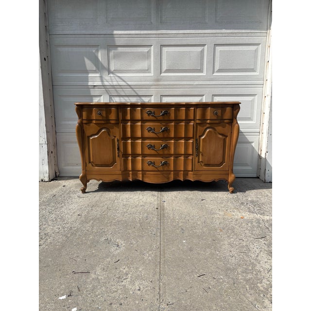 We have a beautiful vintage French Provincial sideboard buffet for sale. It features a gorgeous serpentine front, raised...