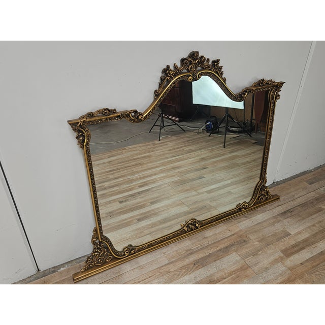 An impressive vintage mirror dating back to the 1960s, featuring a richly carved and lacquered wood frame with an antique...