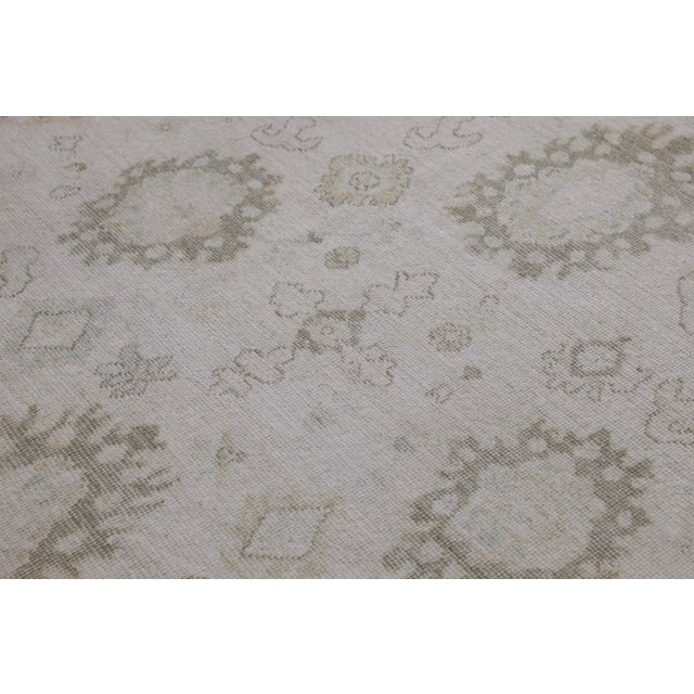 This modern Turkish Oushak rug is a stunning piece of art that has been handwoven using traditional techniques by skilled...