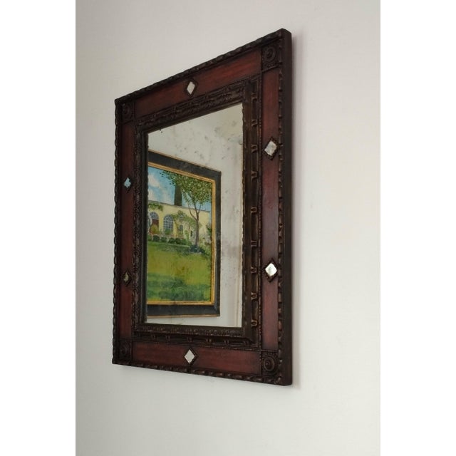 A 1960s Italian Palladio-style mirror with a carved frame and antiqued gold finish. The mirror has been aged to create the...