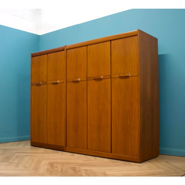 1960s teak triple door wardrobe by Elliots of Newbury, featuring clean lines, a gently curved top rail and integrated...